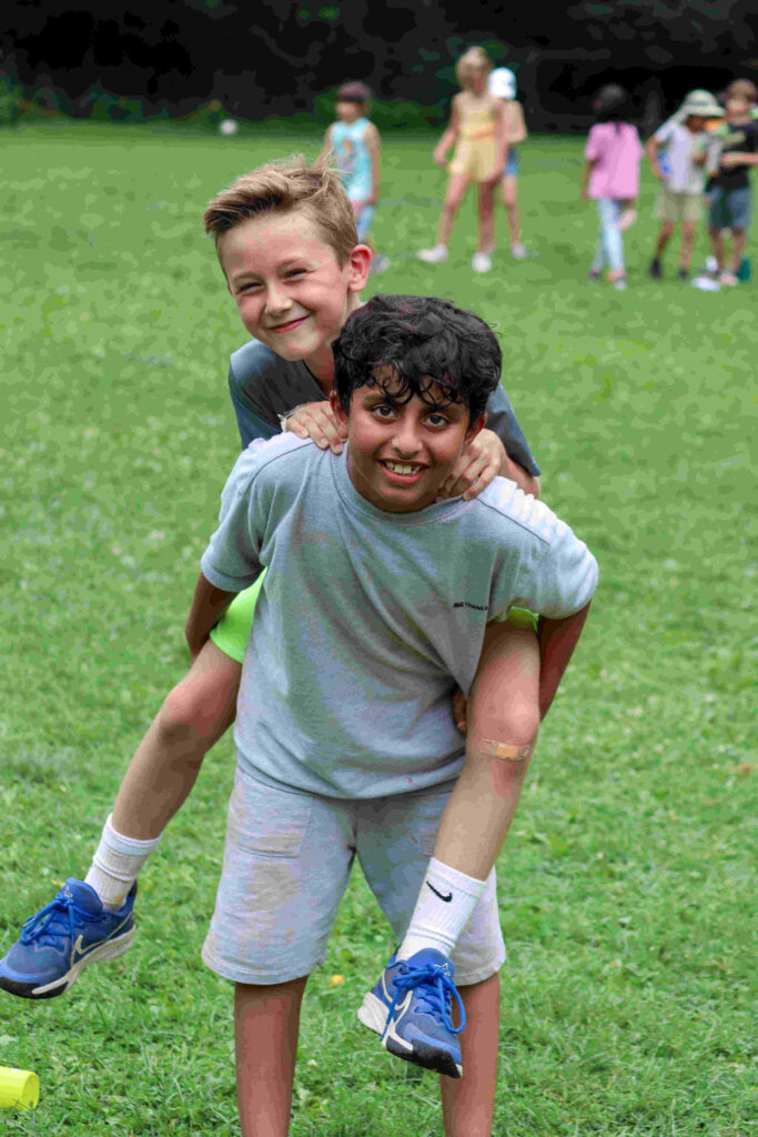 Day Camp. Child being piggy backed by another child during day camp.