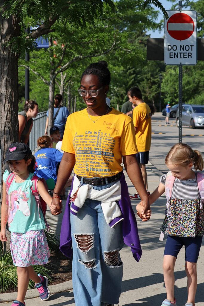 Adventure Valley. Two little girls are walking, holding hands with a counsellor.